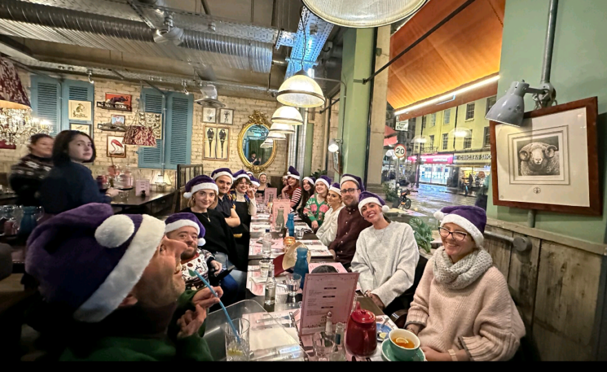 The Purple Goat team celebrating a great year at the Christmas party sat around the restaurant table smiling to camera